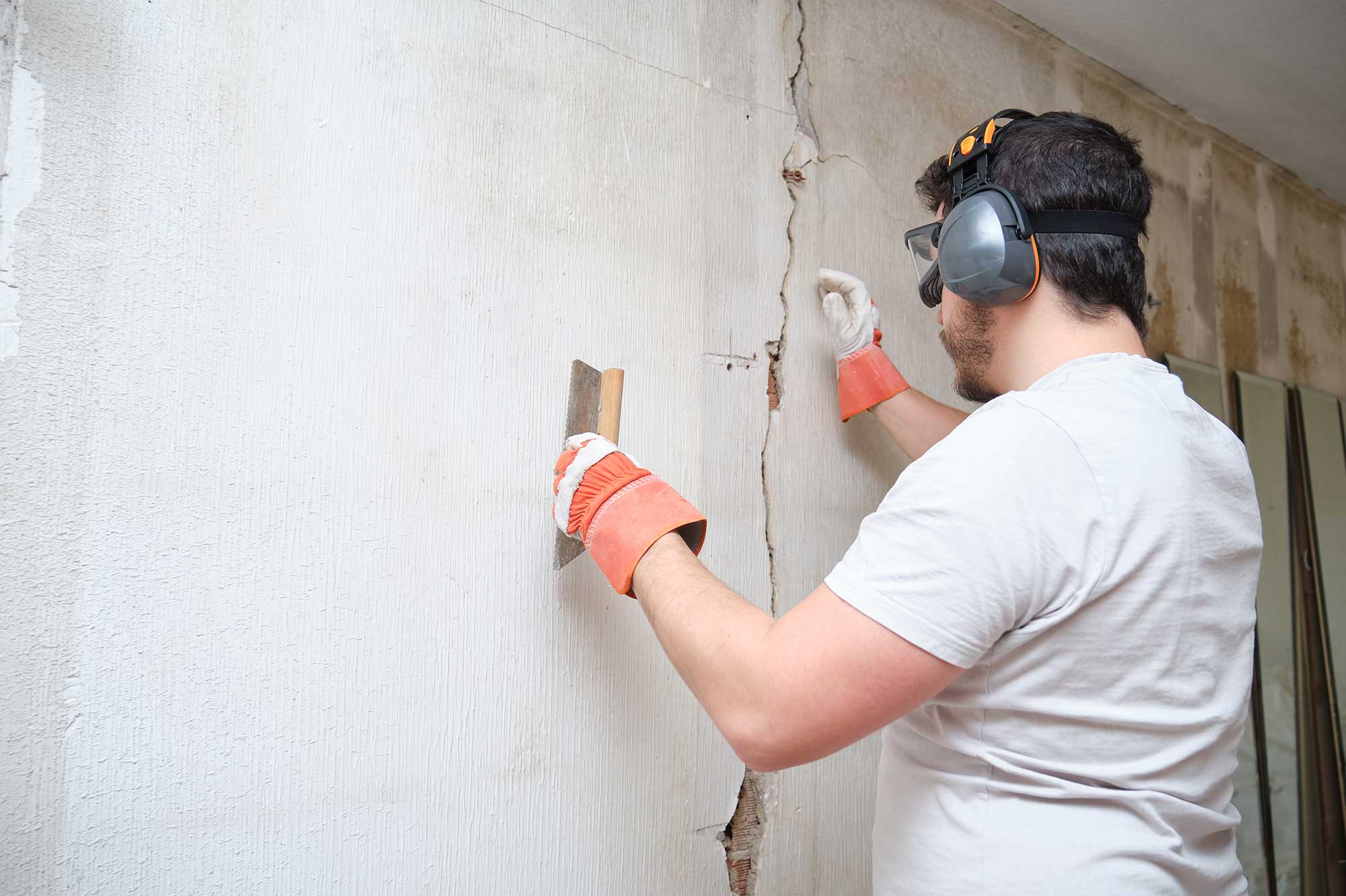 A professional contractor inspecting a damaged drywall wall for repair planning